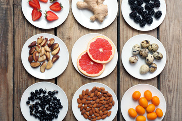 Different products on saucers on wooden table, top view