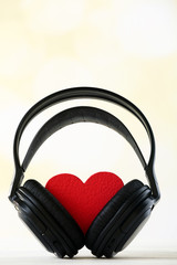Black headphones with red heart on light background