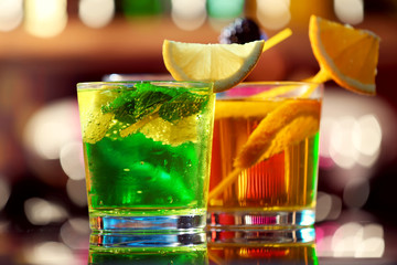 Glasses of cocktails on bar background