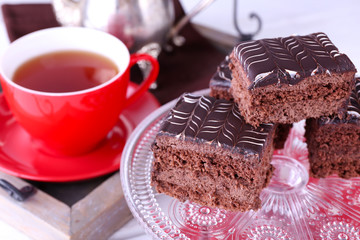 Served table with chocolate cakes and a cup of tea on red dotted background