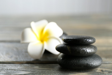 White plumeria flower with pebbles on wooden table