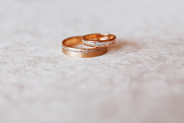Obraz na płótnie Canvas Golden wedding rings with diamonds on white pattern background.