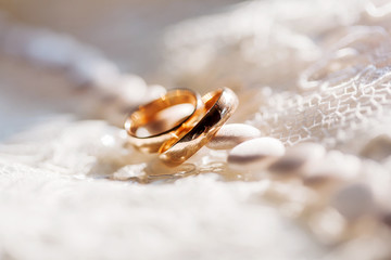 Golden wedding rings on lace silk fabric with buttons. 