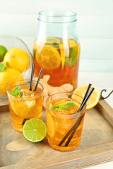Iced tea with lemon on light wooden background