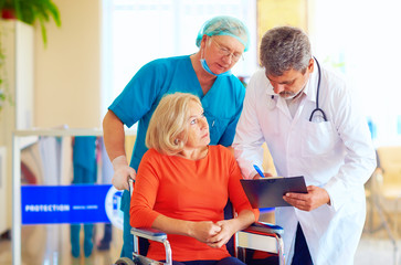 mature female patient on wheelchair listens to doctor prescription medication