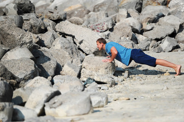 The young man carries out push-ups among stones