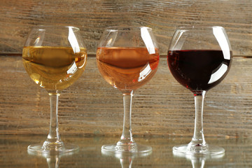 Glasses with white, rose and red wine on wooden background