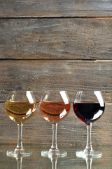 Glasses with white, rose and red wine on wooden background