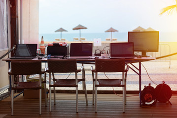 Openair office place with laptops and monitor beside tropical beach