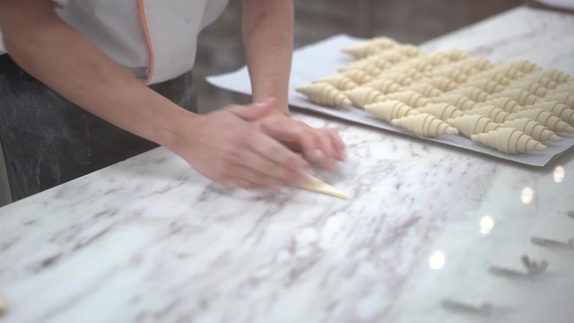 Close up of hand preparing croissant for baking