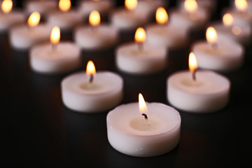 Obraz na płótnie Canvas Alight candles in a row on black background