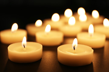 Fototapeta na wymiar Alight candles in a row on black background
