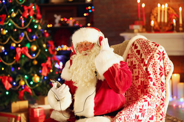 Santa Claus sitting with headphones sitting in comfortable rocking chair at home