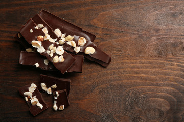 Chocolate pieces with nuts on color wooden background