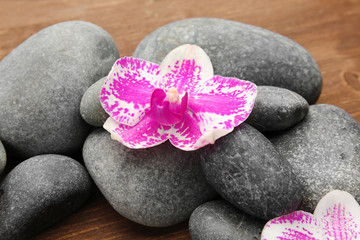 Fototapeta na wymiar Spa stones and orchids on wooden background
