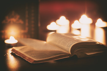 Bible with ghost pages turning and candles in the background 