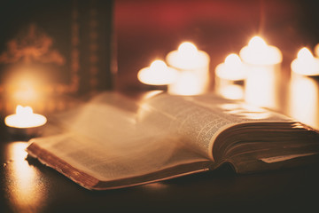 Bible with ghost pages turning and candles in the background 