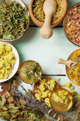 Assortment of dry medicinal herbs in bowls on wooden background top view