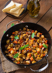 Italian Caponata with frying pan on a wooden background