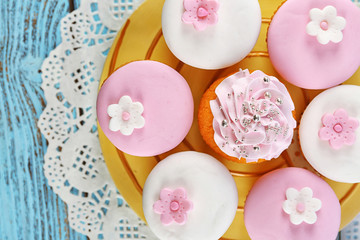 Obraz na płótnie Canvas Tasty cupcakes on plate, on color wooden background