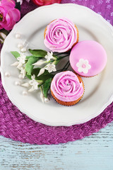 Obraz na płótnie Canvas Tasty cupcakes on plate, on color wooden background