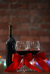 Red wine and Christmas ornaments on wooden table on wall brick background with Christmas lights