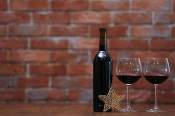 Red wine and Christmas ornaments on wooden table on wall brick background