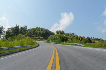 Curve of empty road and green field in country at nan thailand