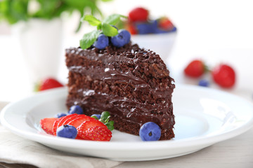 Chocolate cake with chocolate cream and fresh berries on plate, on light background