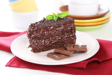 Chocolate cake with chocolate cream on plate, on light background