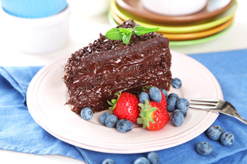 Chocolate cake with chocolate cream and fresh berries on plate, on wooden background