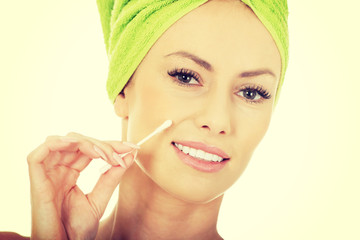 Woman removing make up with cotton bud.