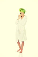 Spa woman in bathrobe holding orange.