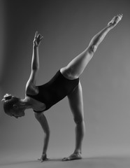 Modern ballet dancer posing on dark background