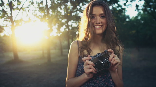 young female holds an old camera and smiles slow motion
