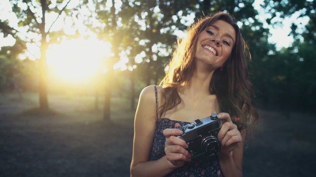 young female holds an old camera and smiles slow motion