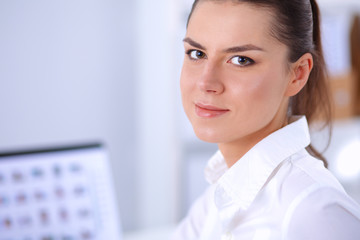 Attractive businesswoman sitting on a desk with laptop in the office