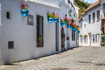 Picturesque street of Mijas with flower pots in facades. Andalus