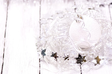 Magic Chrismas Card. Sparkle xmas ball nested in lights. Wooden white background. Selective focus