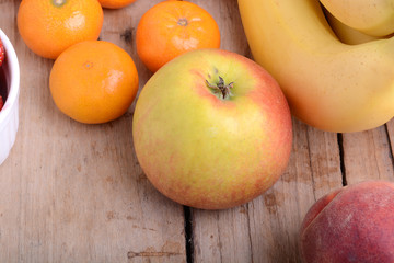 Mandarin Apples Bananas Peach on wooden plate