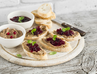 Sandwiches with chicken liver pate and cranberry sauce, served on a light wooden board
