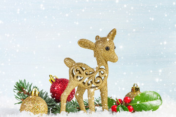 Fawn with fir branch and holly leaves in the snow.  Christmas ba