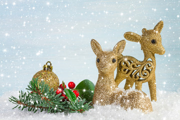 The family of deer with branch fir and holly leaves in the snow.