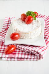 Ein runder Camembert mit Cocktailtomaten auf einem Teller