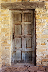 Fototapeta na wymiar Wooden Door against Worn Stone Wall / An Interesting View of a Rustic Wooden Door against Worn Stone Wall