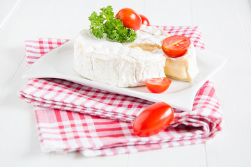 Ein runder Camembert mit Cocktailtomaten auf einem Teller