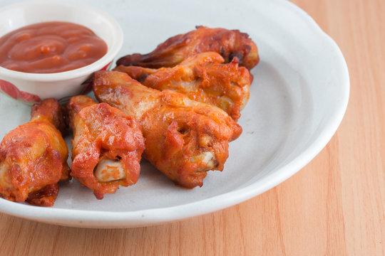 Chicken wings with sauce in dish on wooden table.
