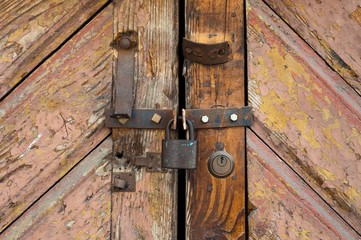 Rusty old padlock locking a wooden door