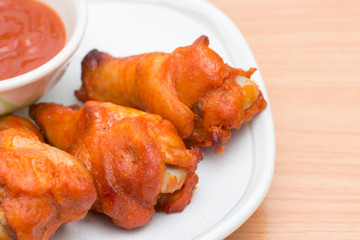 Chicken wings with sauce in dish on wooden table.