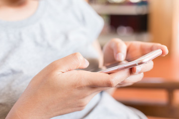 young woman holding a smart phone on the background of cafe, soft and selective focus